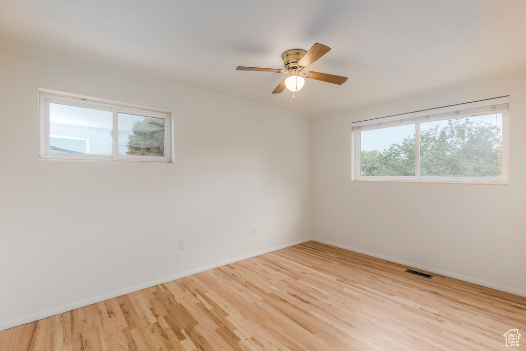 Spare room with wood finished floors, a ceiling fan, and ornamental molding