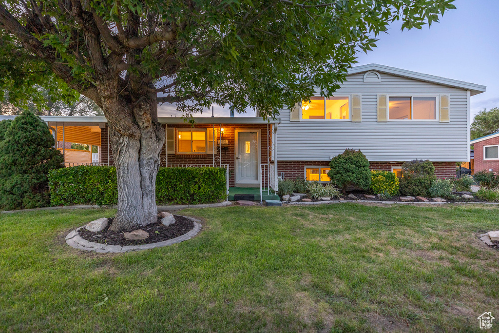Split level home with a front yard, a porch, and brick siding