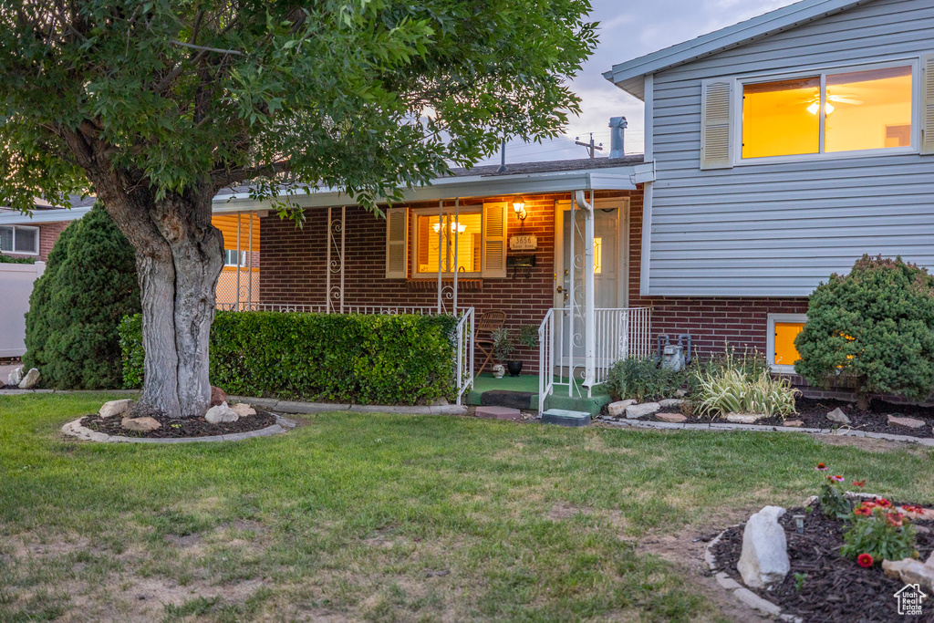 Tri-level home featuring brick siding, a front lawn, and a porch