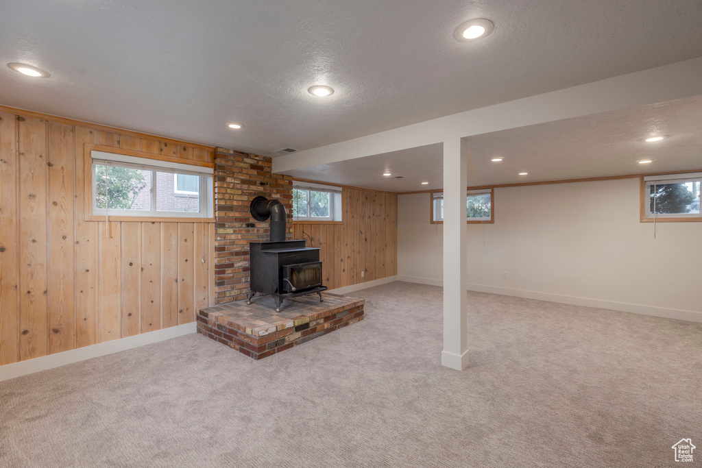 Below grade area featuring wood walls, a wood stove, carpet flooring, recessed lighting, and a textured ceiling