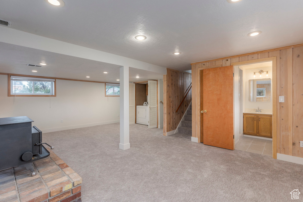 Basement with a wood stove, light colored carpet, stairs, recessed lighting, and wooden walls
