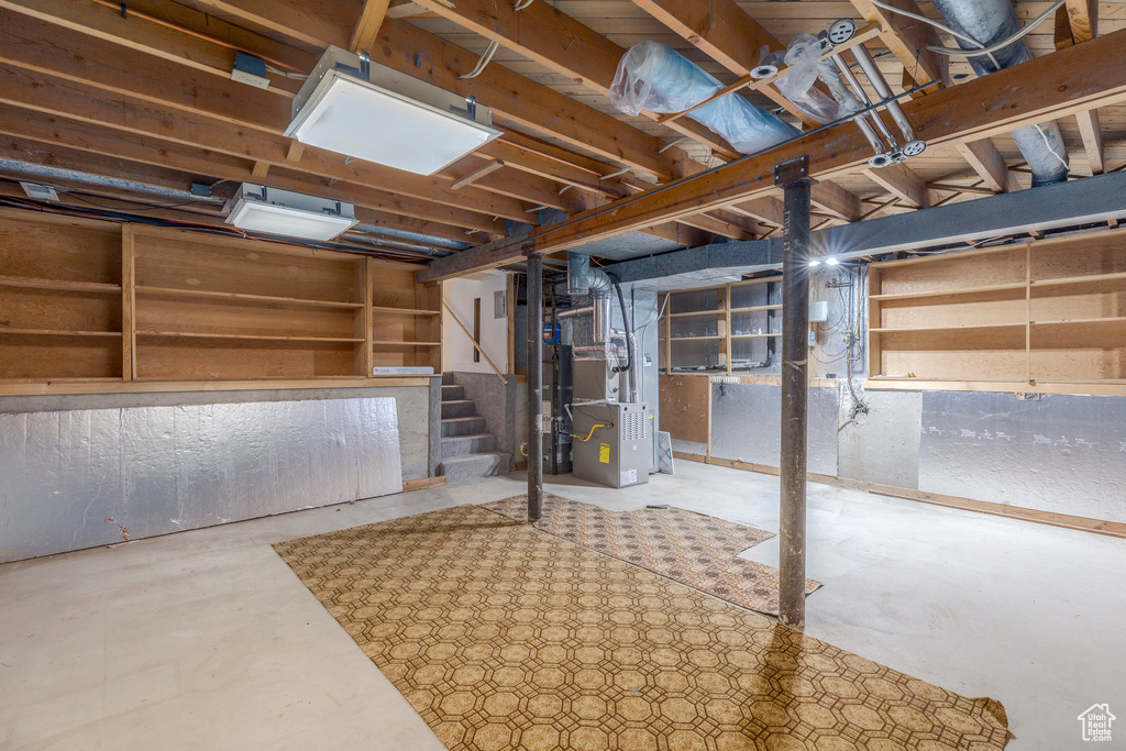 Unfinished basement with stairs and heating unit