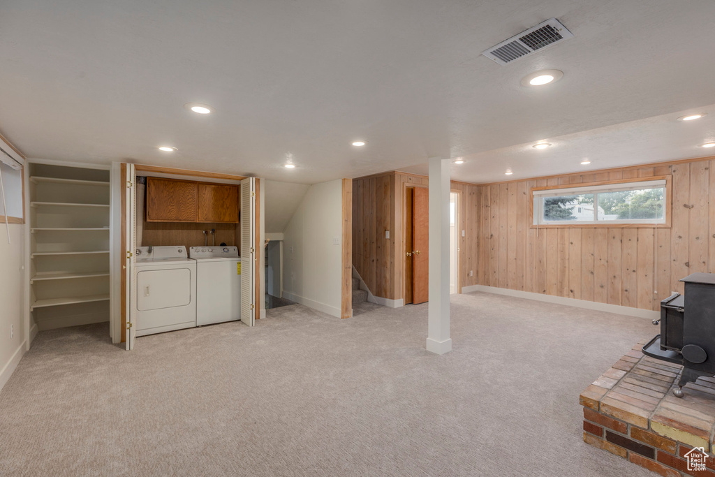 Below grade area with washing machine and dryer, stairs, a wood stove, recessed lighting, and wood walls