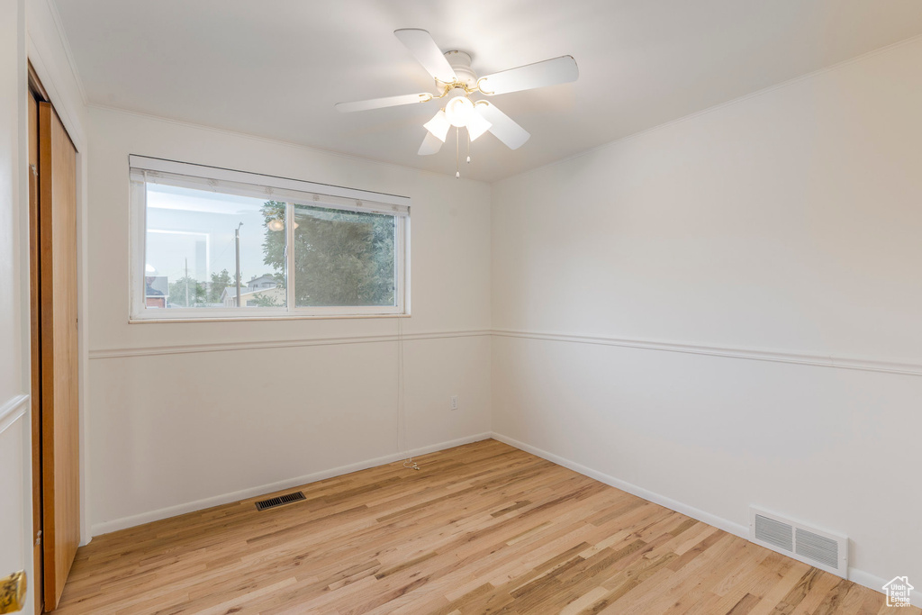Empty room featuring light wood-style flooring and ceiling fan
