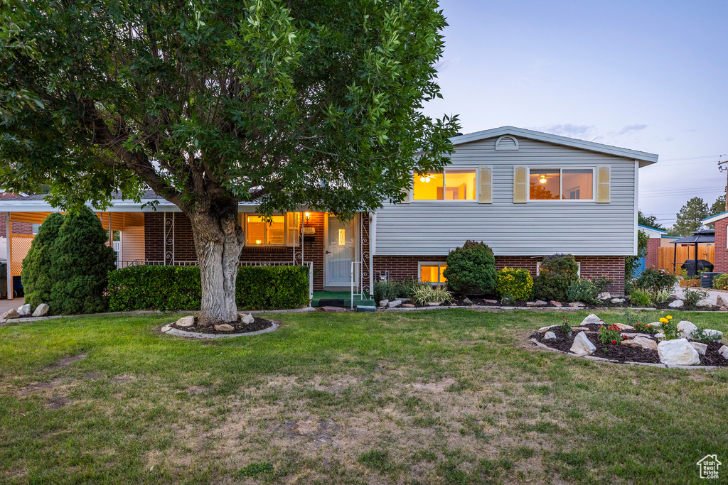 Tri-level home with a front yard and brick siding