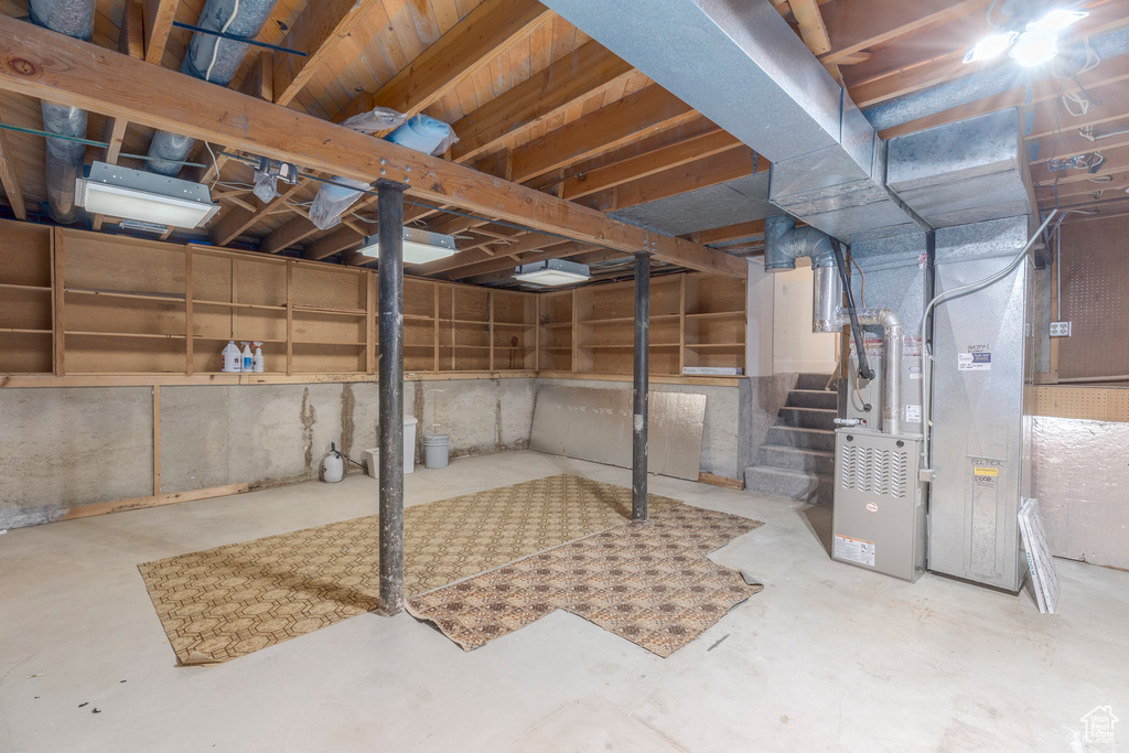 Unfinished below grade area featuring heating unit and stairway