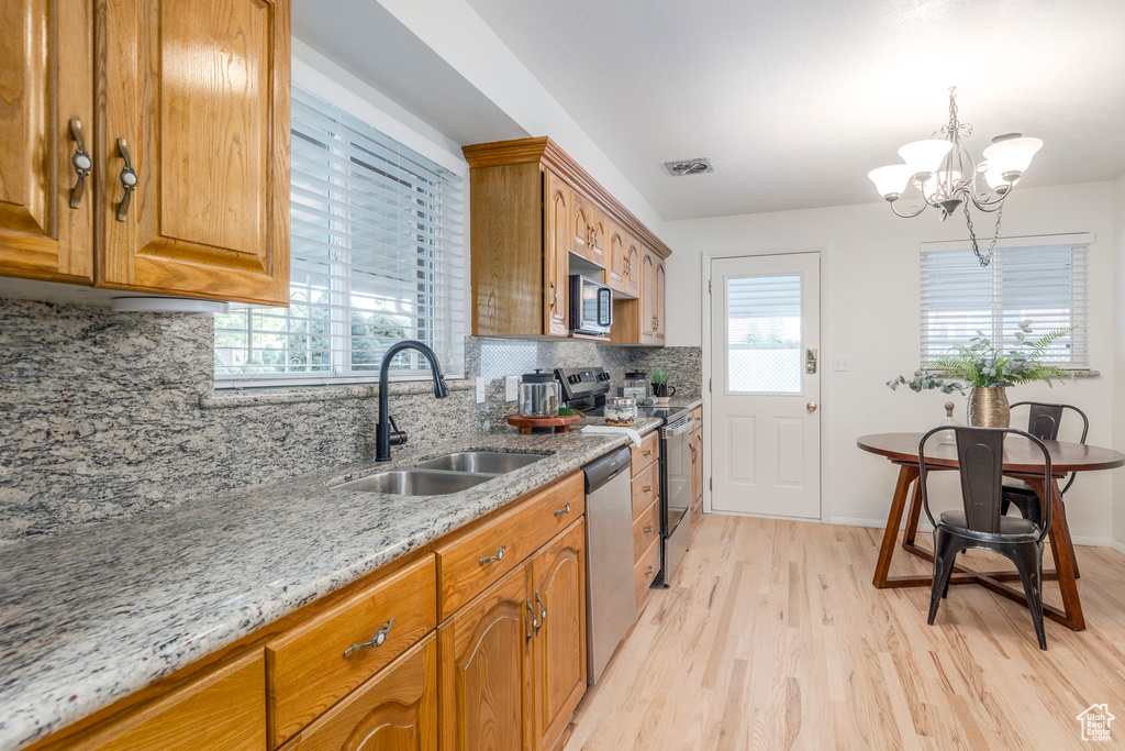 Kitchen featuring light wood-style floors, appliances with stainless steel finishes, light stone countertops, and healthy amount of natural light