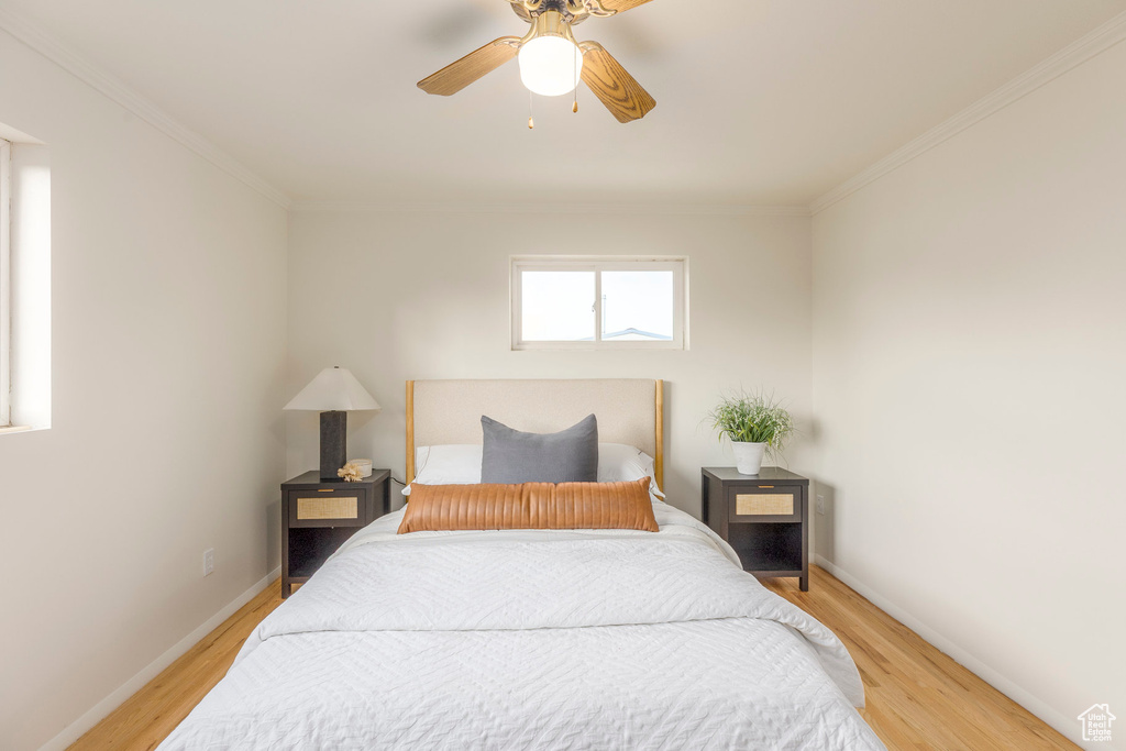 Bedroom featuring light wood-style flooring, ornamental molding, and a ceiling fan