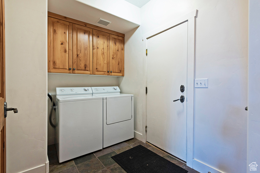 Laundry area featuring cabinet space, washer and dryer, and stone finish flooring