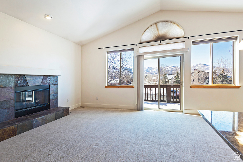 Unfurnished living room with lofted ceiling, carpet floors, a fireplace, and a mountain view