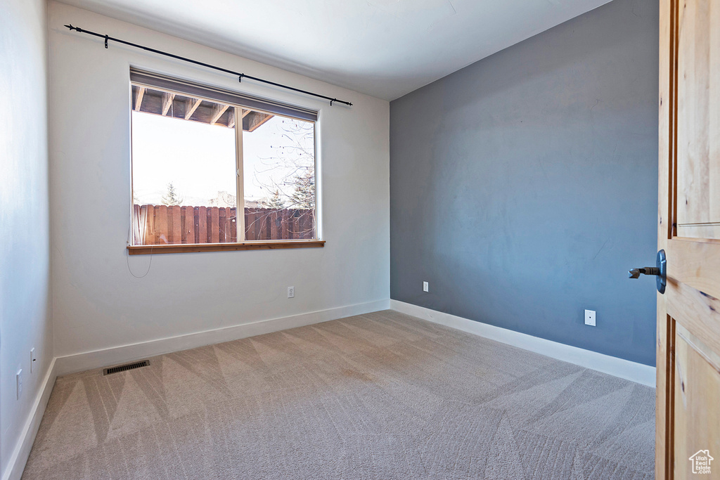 Carpeted spare room featuring baseboards