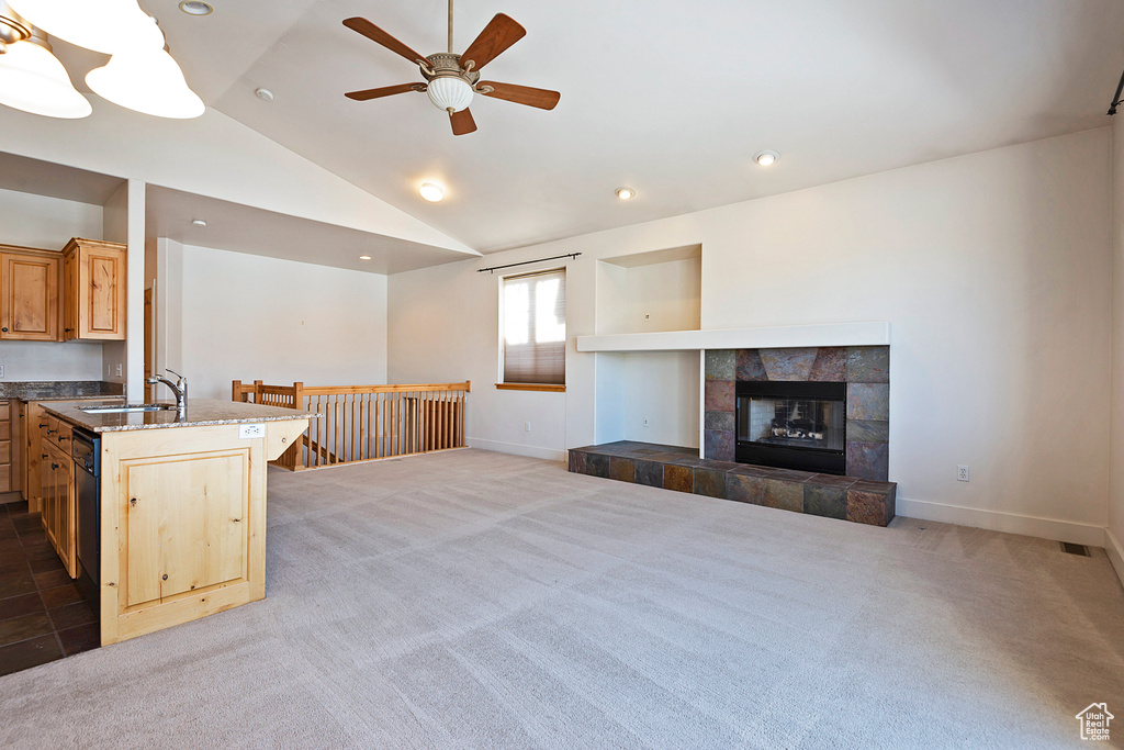 Living area with ceiling fan, light carpet, vaulted ceiling, recessed lighting, and a tile fireplace