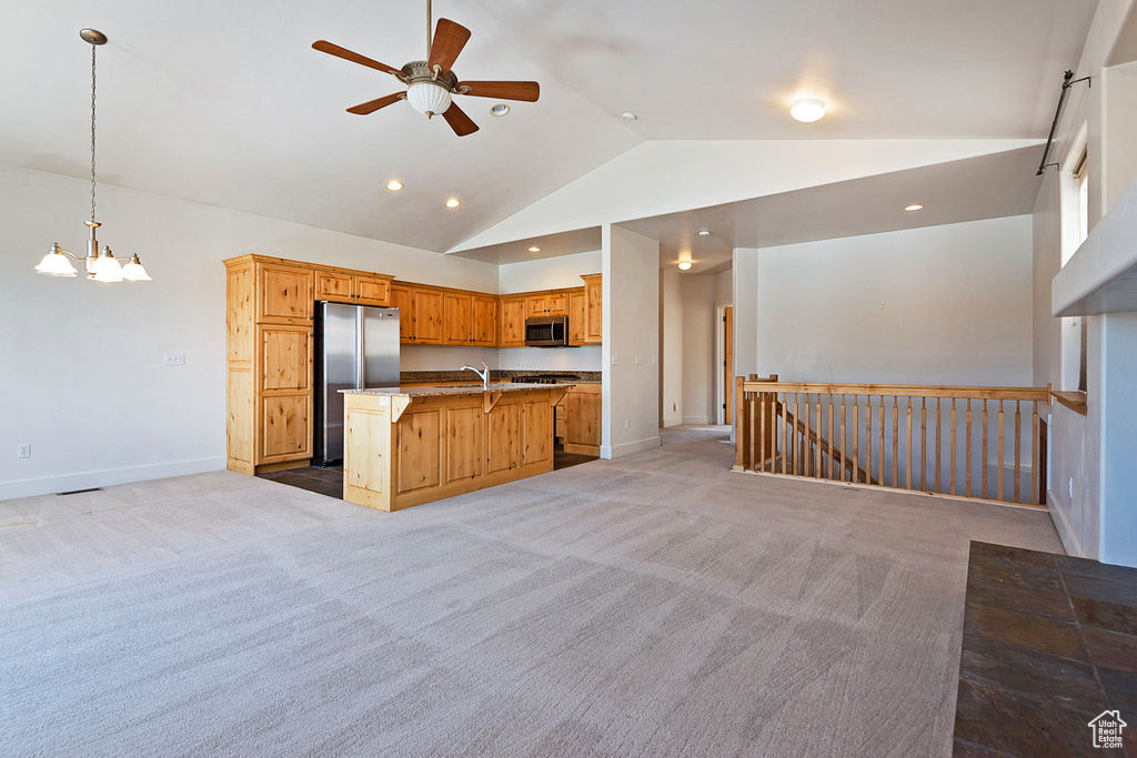 Kitchen featuring open floor plan, appliances with stainless steel finishes, lofted ceiling, ceiling fan, and light carpet