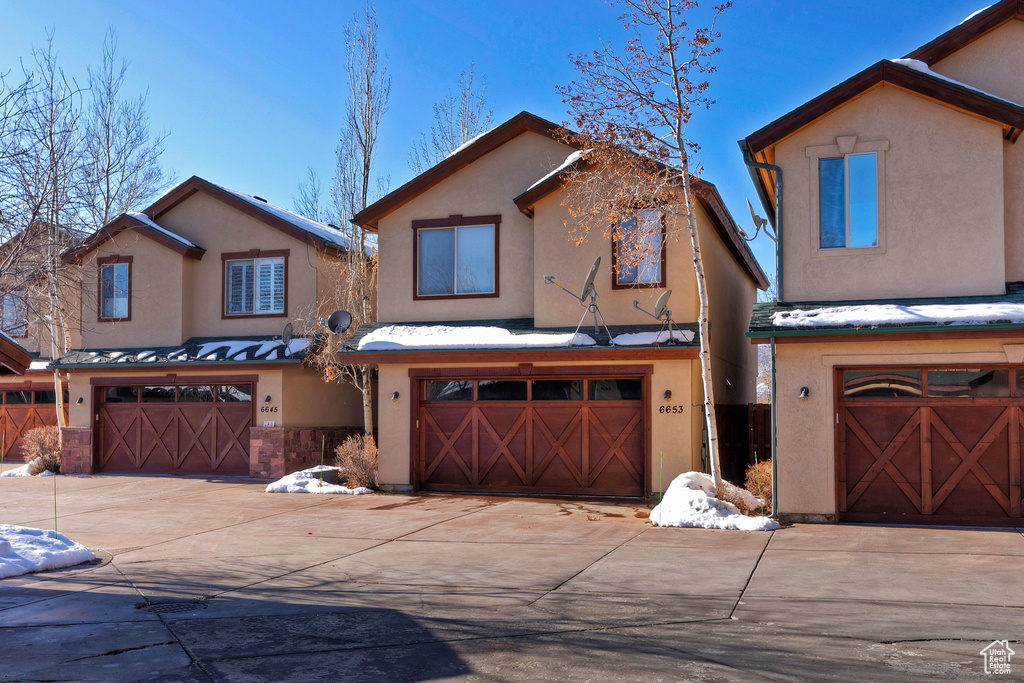 View of front of home with an attached garage, stucco siding, and driveway