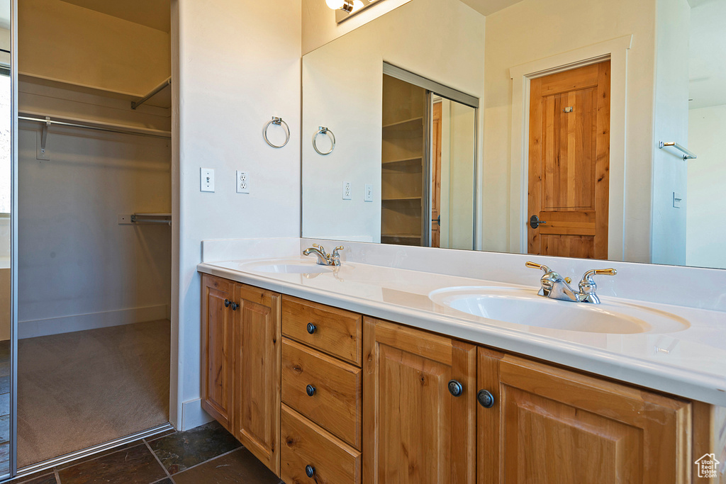 Bathroom with double vanity and a walk in closet