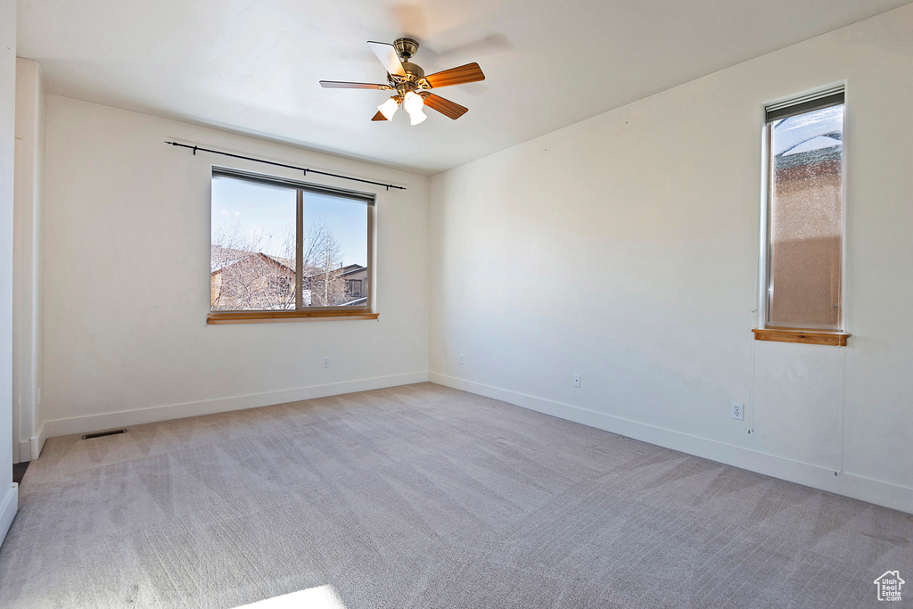 Unfurnished room with plenty of natural light, a ceiling fan, and light colored carpet