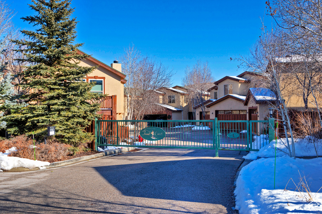 View of front of home with stucco siding, a chimney, a gate, and a residential view