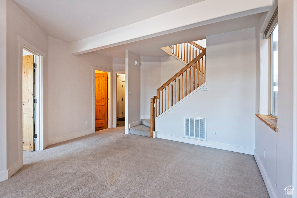 Unfurnished living room with carpet flooring and stairway