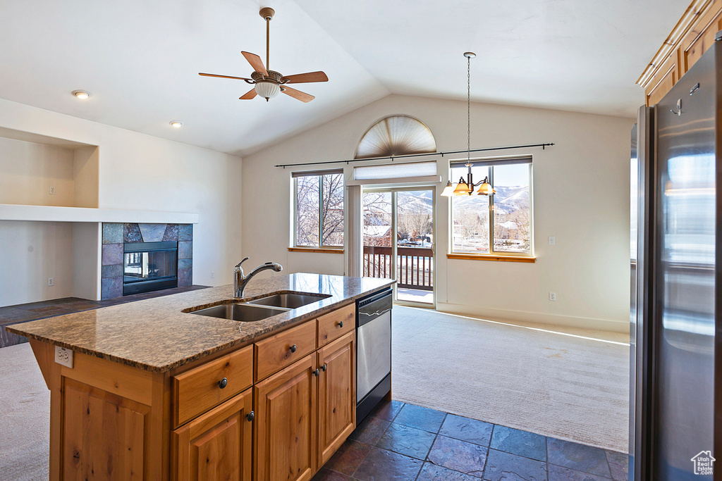 Kitchen with stainless steel appliances, open floor plan, dark colored carpet, a ceiling fan, and lofted ceiling