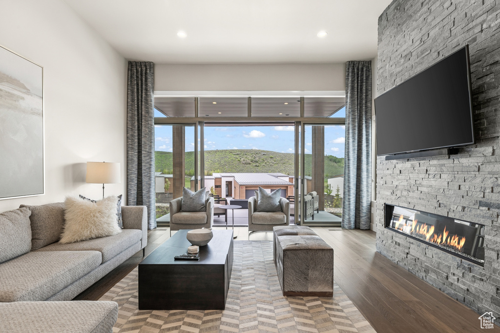 Living room with a stone fireplace, wood finished floors, and recessed lighting