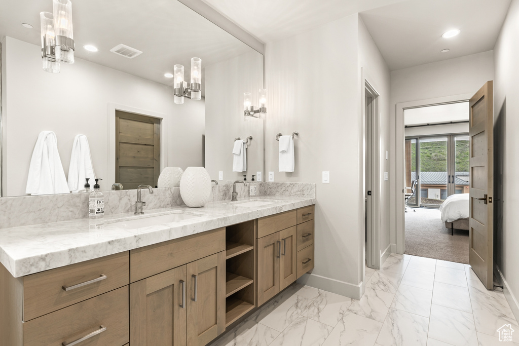 Ensuite bathroom featuring double vanity, recessed lighting, and marble finish flooring