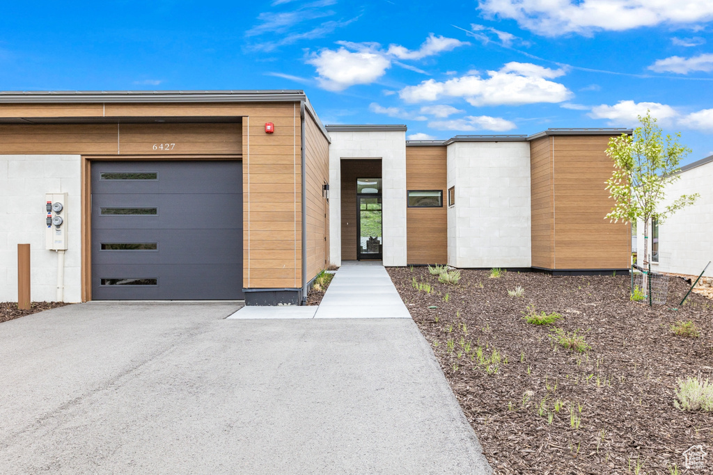 View of front of house featuring concrete block siding, driveway, and a garage