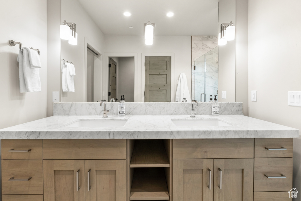 Full bath with double vanity, recessed lighting, and a marble finish shower