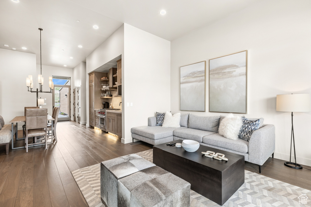 Living room with dark wood finished floors, a chandelier, and recessed lighting