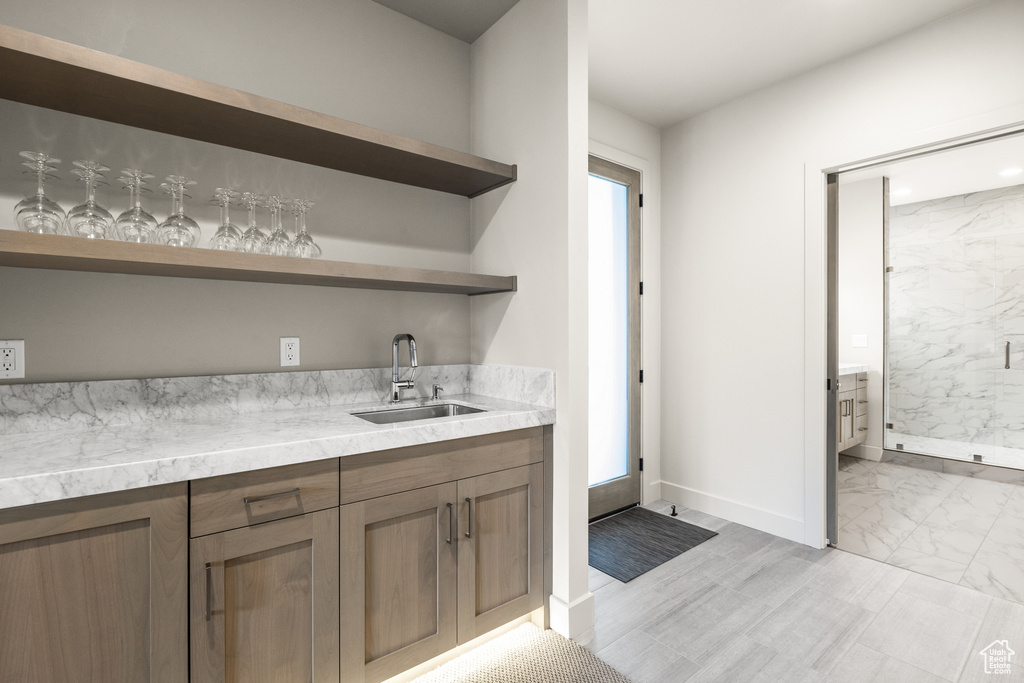 Indoor wet bar with light marble finish flooring and baseboards