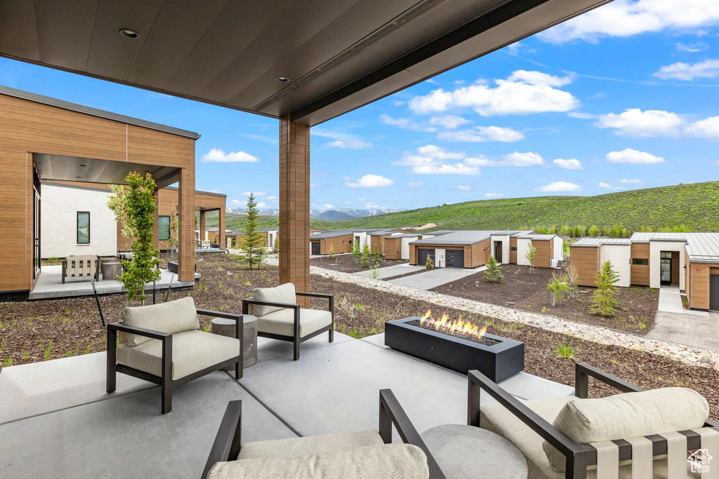 View of patio with a mountain view, an outdoor living space with a fire pit, an outbuilding, and a residential view