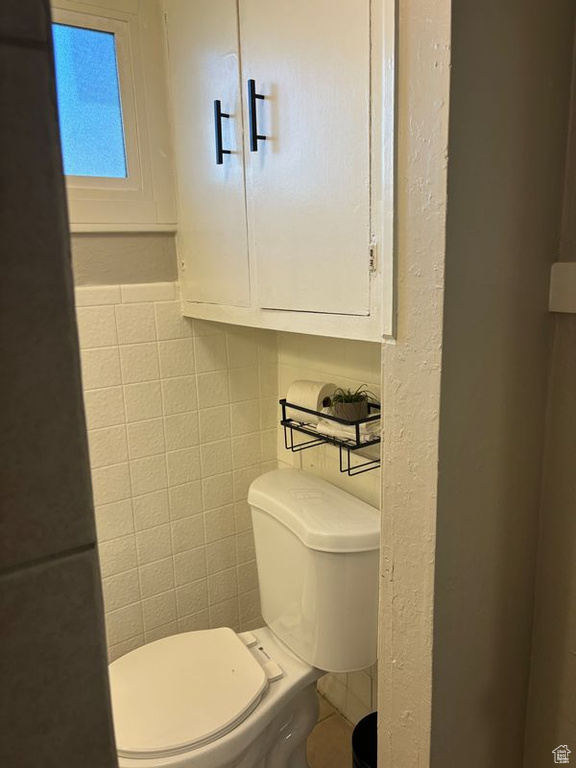 Half bath featuring toilet and tile walls