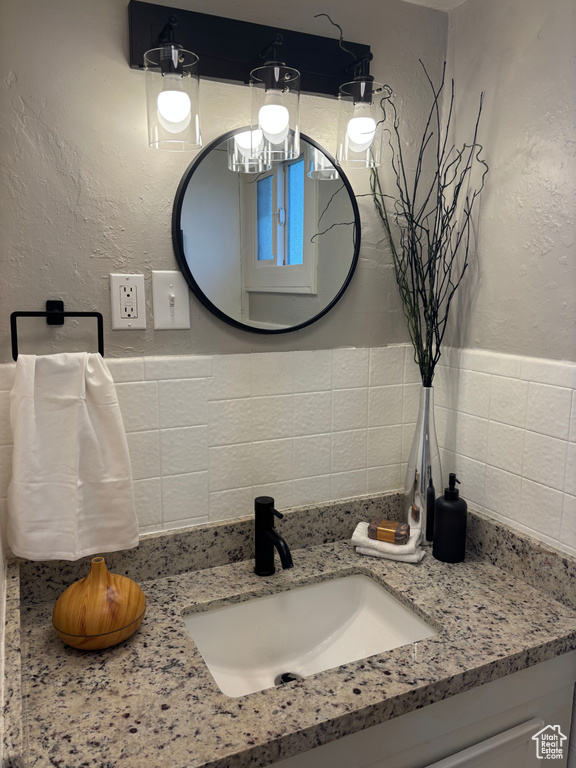 Bathroom with vanity, a chandelier, and a textured wall