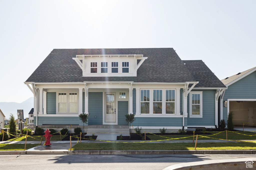 View of front of home featuring roof with shingles, a front lawn, and a garage