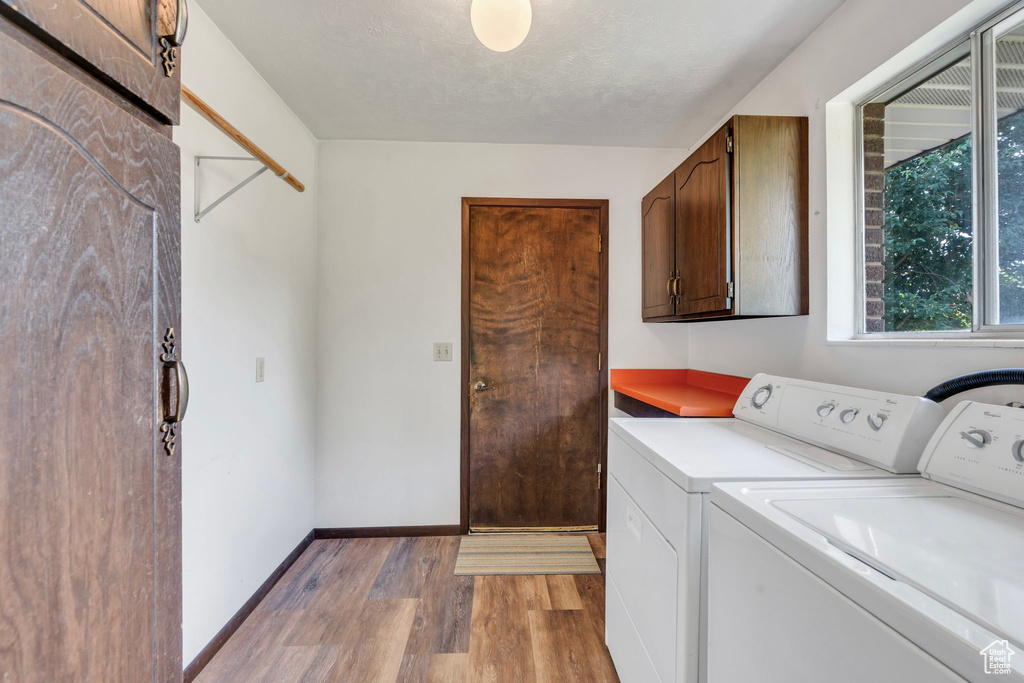 Laundry area featuring separate washer and dryer, cabinet space, and light wood-type flooring