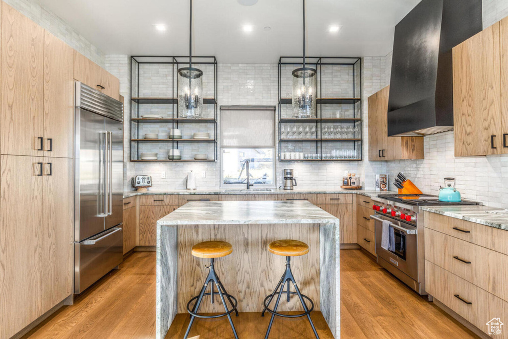 Kitchen with light brown cabinets, a kitchen island, open shelves, and high quality appliances