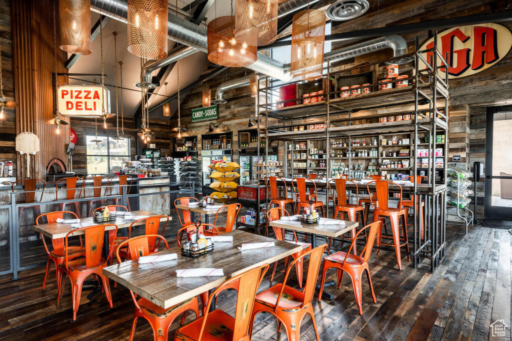 Dining space with a high ceiling, wooden walls, and hardwood / wood-style flooring