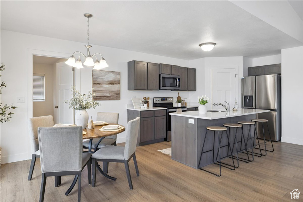 Kitchen featuring appliances with stainless steel finishes, a breakfast bar area, light wood-style flooring, light countertops, and dark brown cabinets