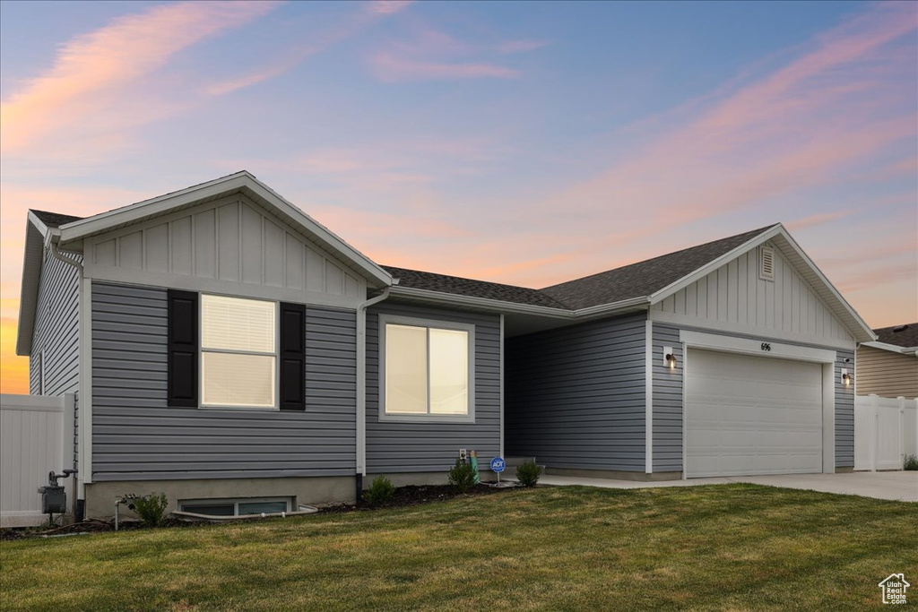 View of front facade with board and batten siding, an attached garage, driveway, and a shingled roof