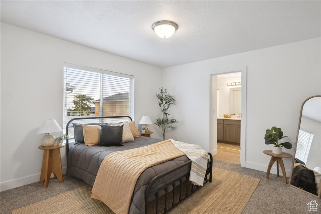 Bedroom featuring light carpet and connected bathroom