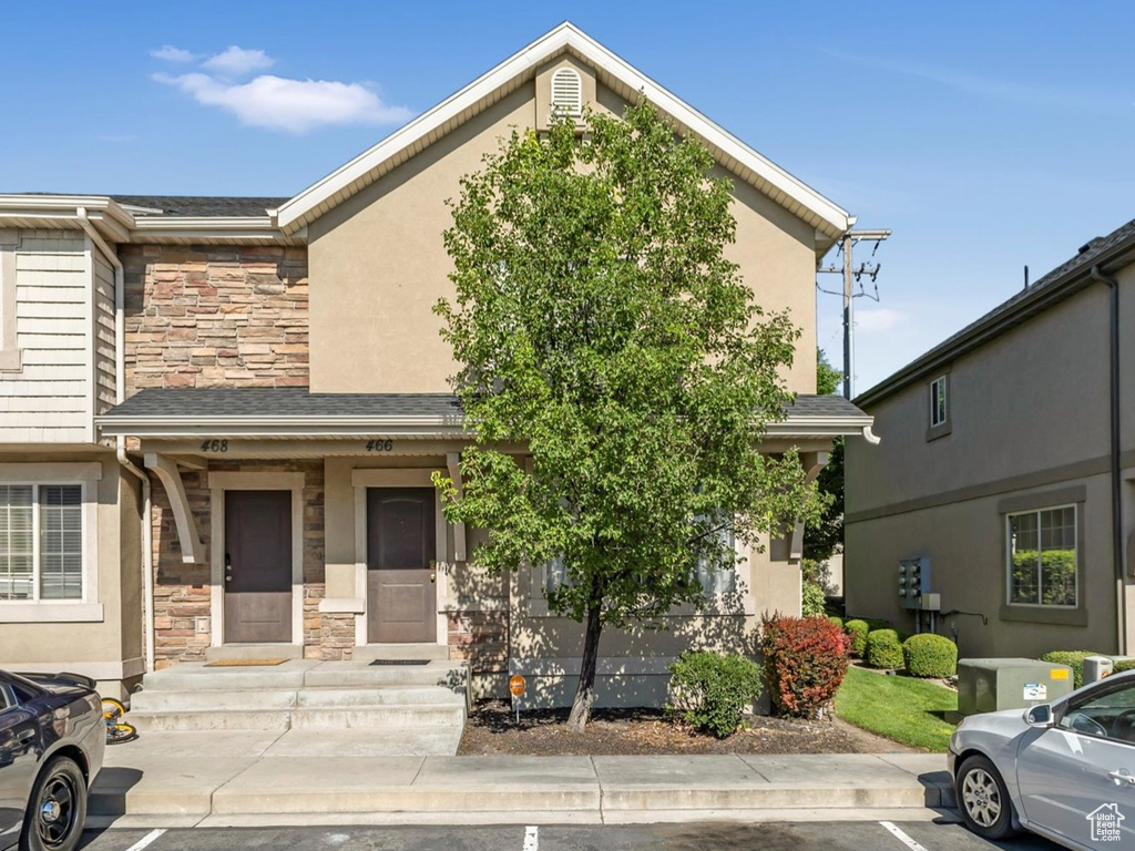 Townhome / multi-family property featuring stone siding, uncovered parking, and stucco siding