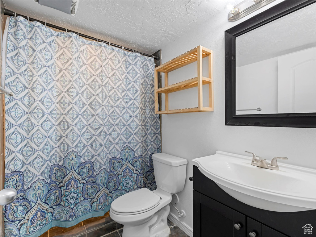 Full bathroom with vanity, a textured ceiling, and curtained shower