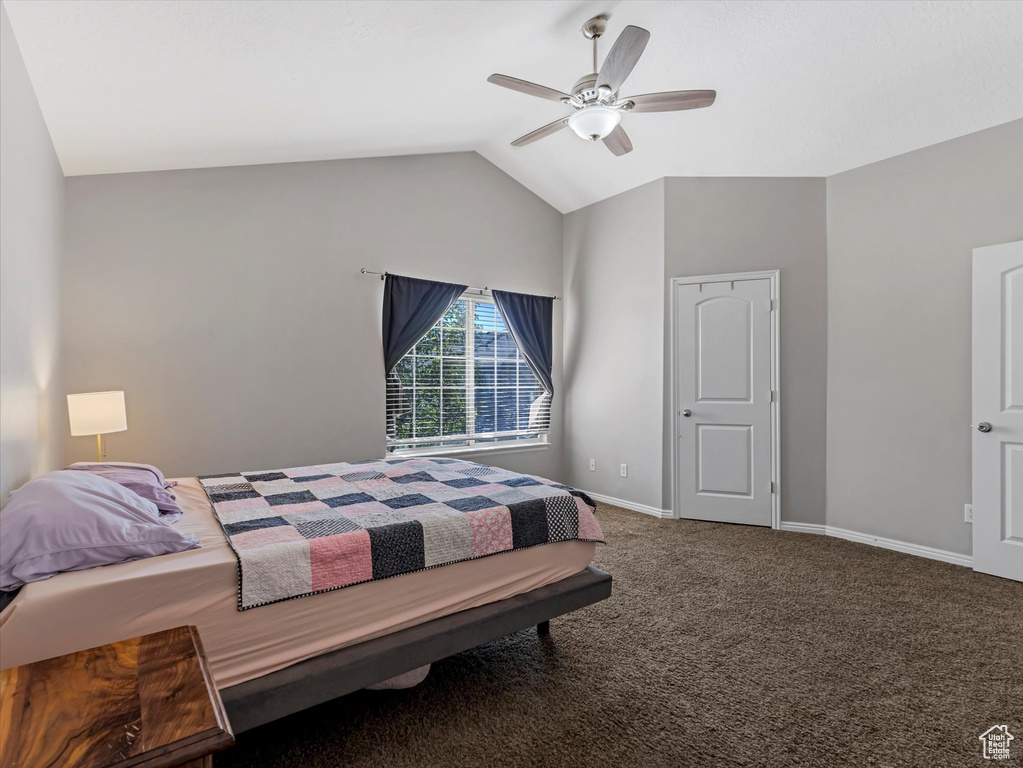 Carpeted bedroom featuring vaulted ceiling and ceiling fan