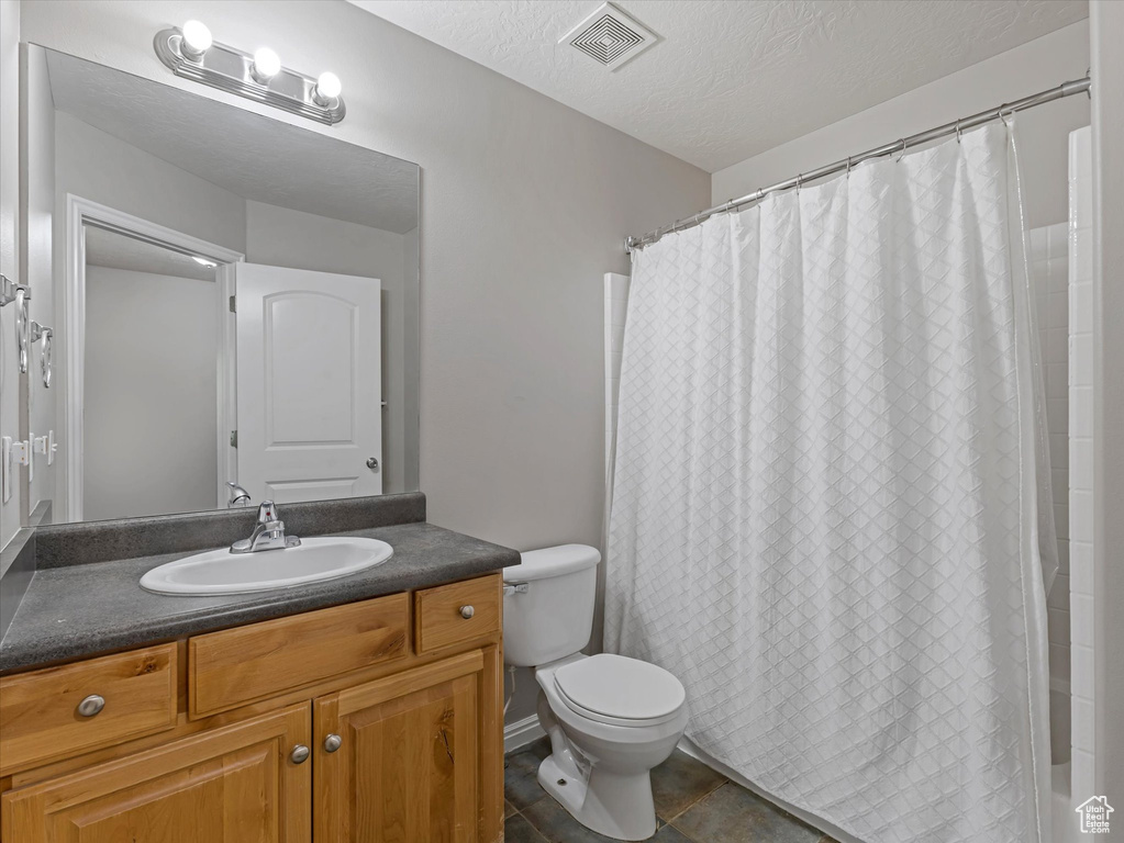 Bathroom featuring vanity, tile patterned flooring, and a textured ceiling