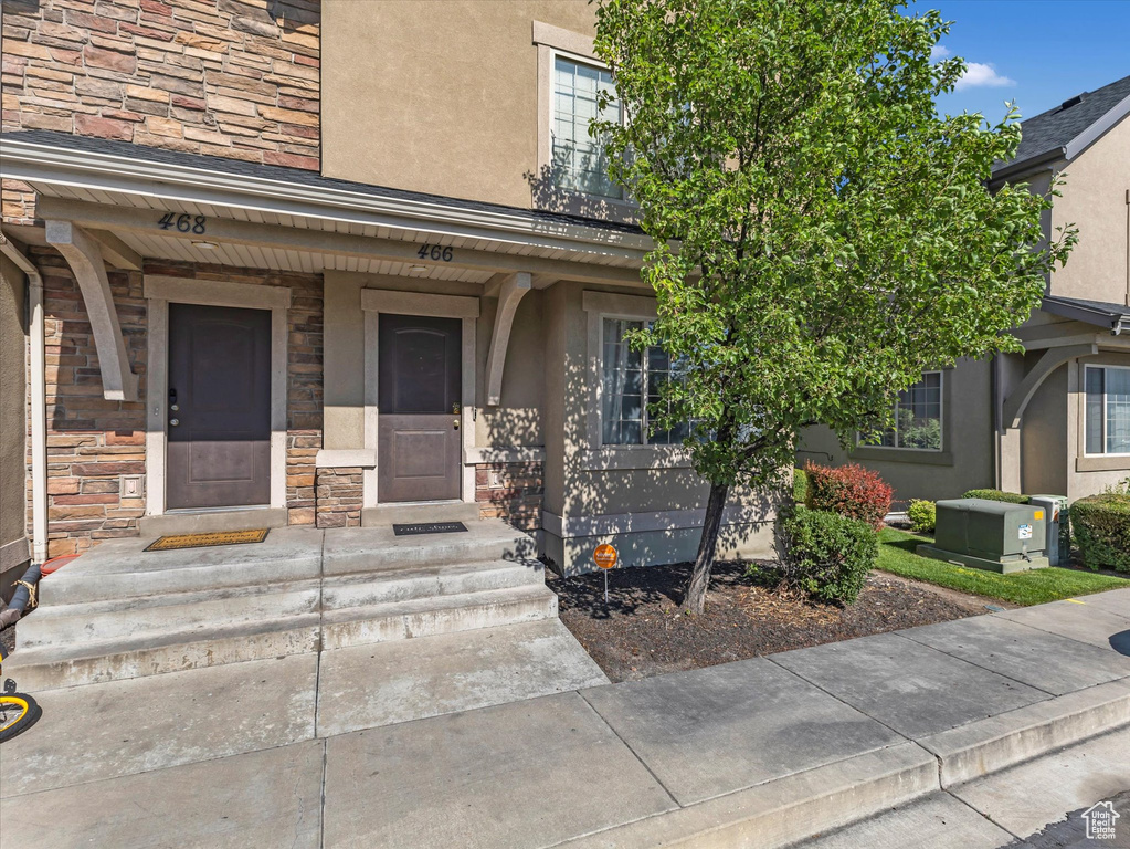 Property entrance with stone siding, stucco siding, and a porch