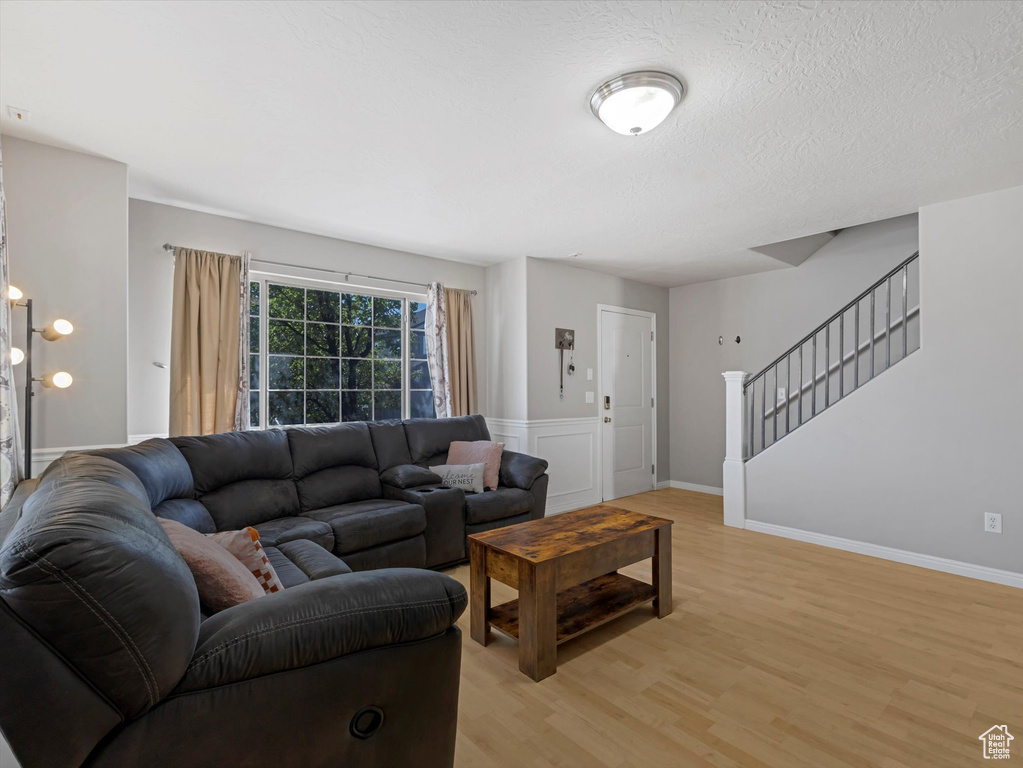 Living room featuring light wood-style flooring, stairs, and a textured ceiling