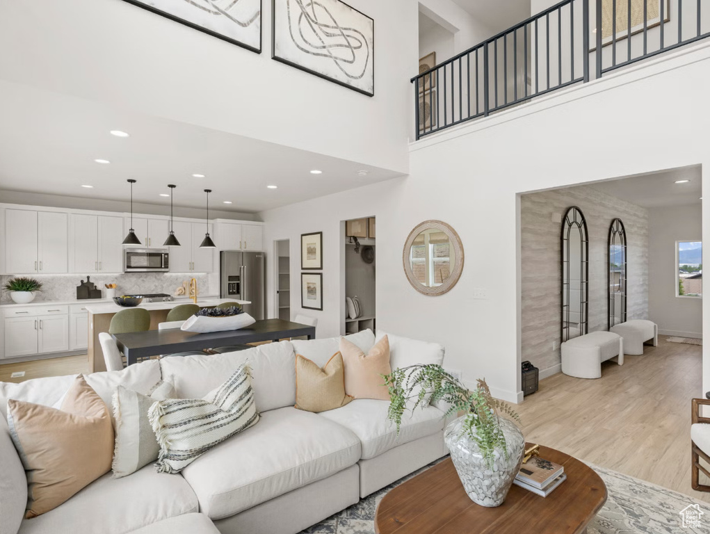 Living room featuring light wood finished floors, recessed lighting, and a towering ceiling