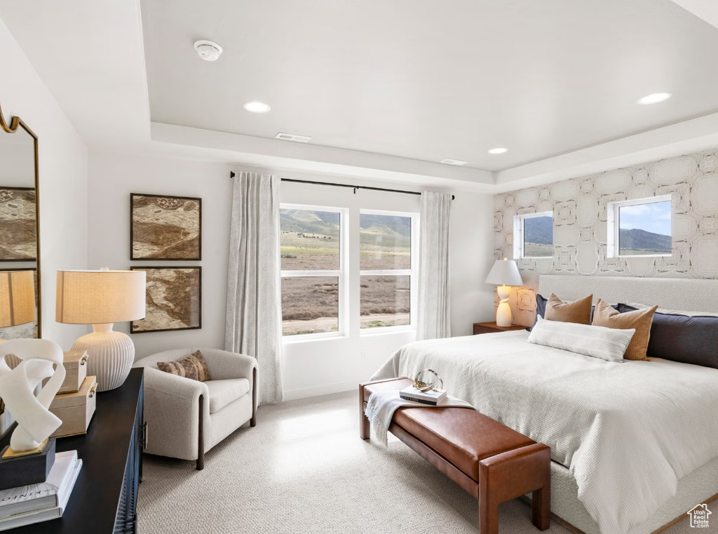 Carpeted bedroom featuring a raised ceiling, recessed lighting, and multiple windows