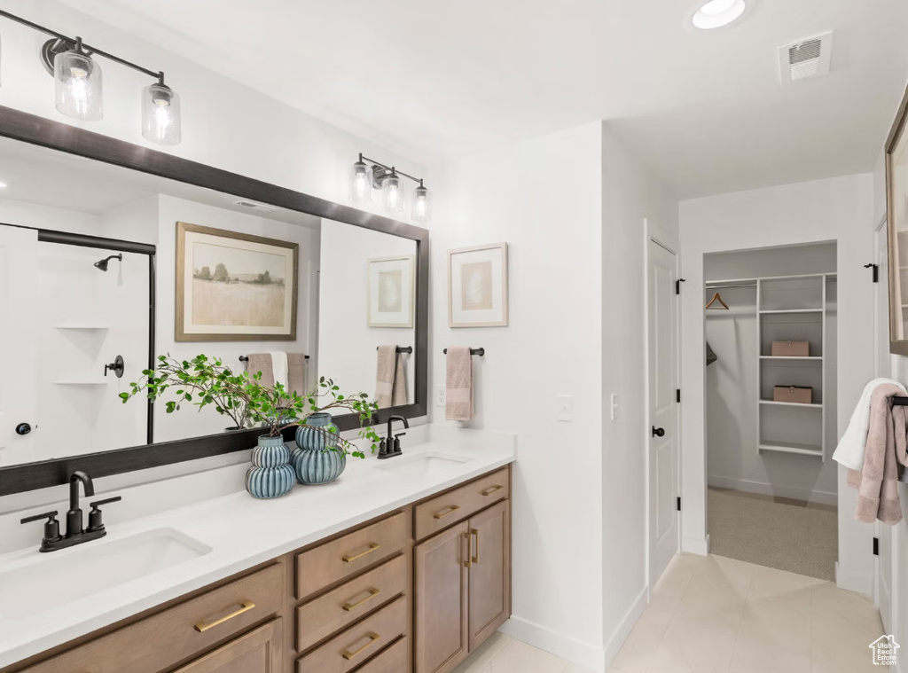 Bathroom with double vanity, a spacious closet, and recessed lighting
