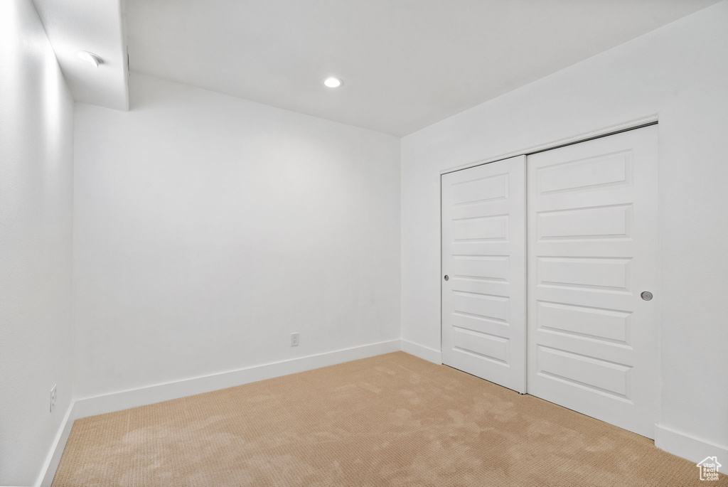 Unfurnished bedroom with light colored carpet, a closet, and recessed lighting