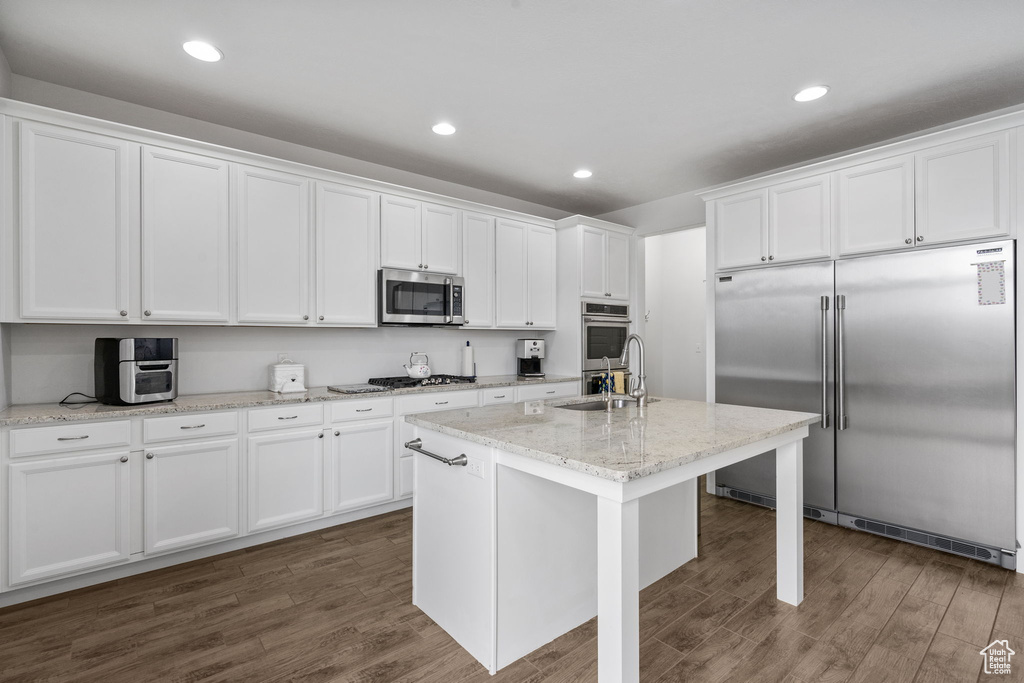 Kitchen with appliances with stainless steel finishes, dark wood finished floors, white cabinets, and recessed lighting